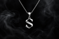 The Saintarini S Pendant in white gold — the house letterform on a dark backdrop (placeholder image, to be replaced with the production photograph)